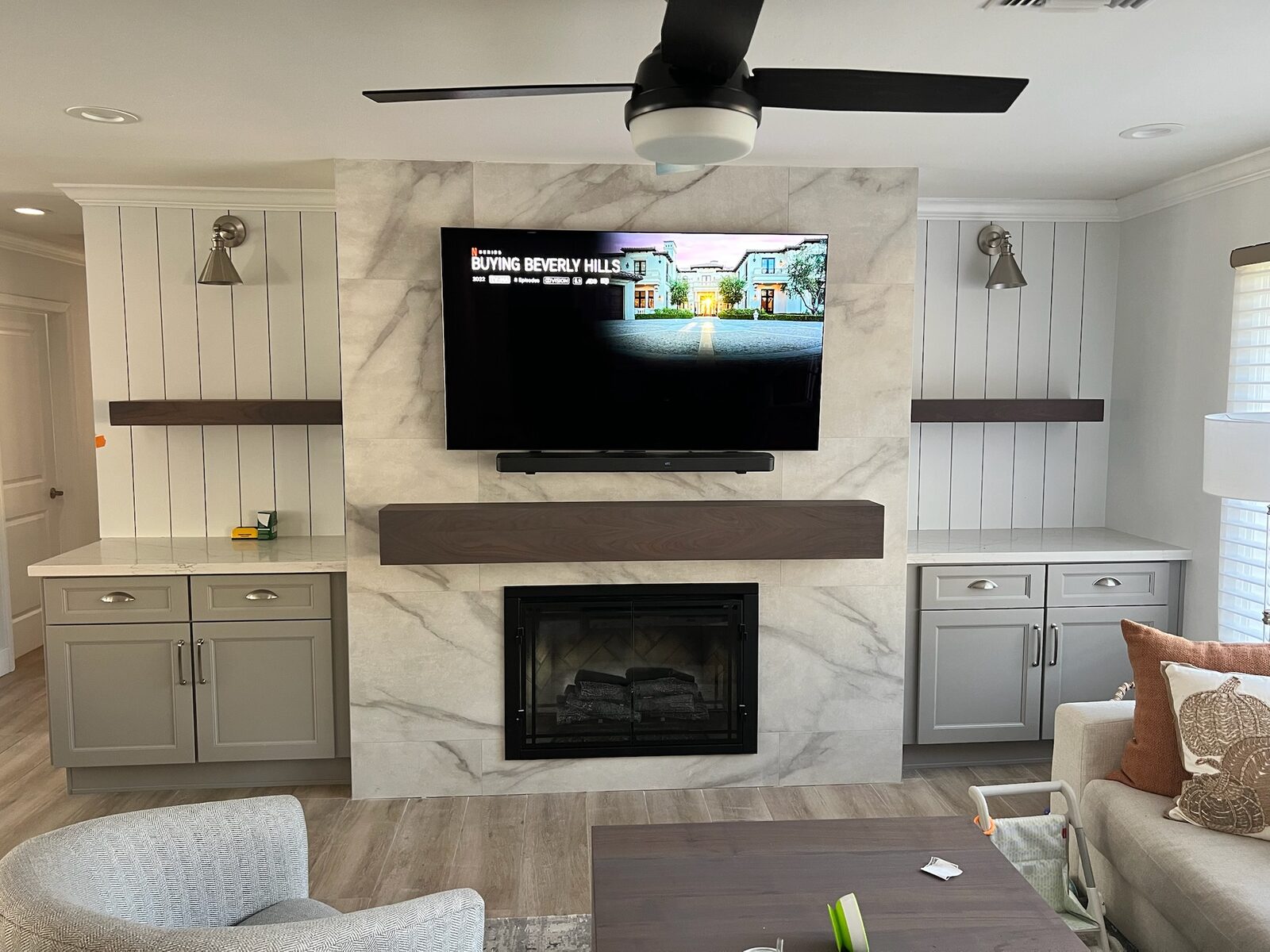 Finished living room wall with tiled fireplace surround, floating mantel, shiplap built-ins and a mounted television